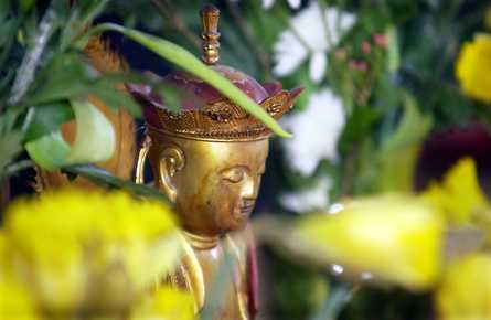 Statue of Dizang (Ksitigarbha, Jizo) with daffodils