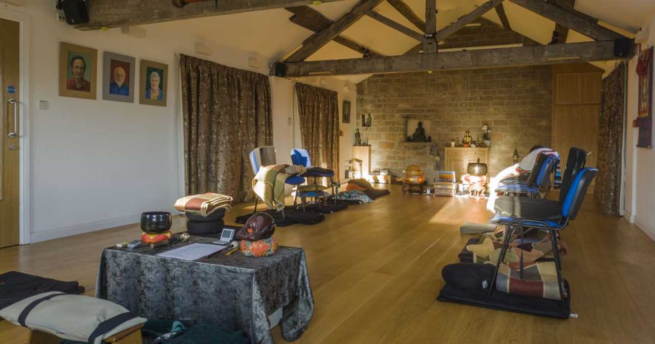 Meditation hall with exposed roof trusses and sunbeams lighting the Buddha statues
