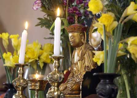 Statue of Dizang (Ksitigarbha, Jizo) with daffodils and candles